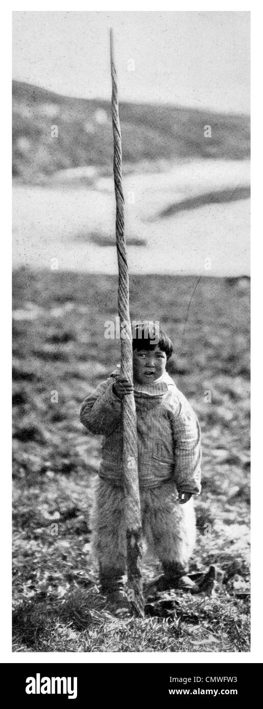 1925 Eskimo child with the helical tusk of a Narwhal Monodon monoceros Stock Photo