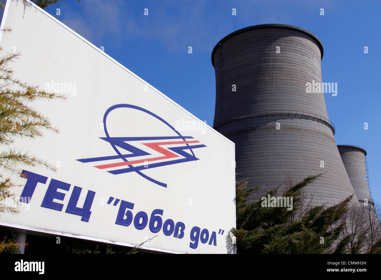 Sign with company logo 'TETs Bobov Dol' (thermo-electric power plant Bobov Dol) and two cooling towers against blue sky Stock Photo