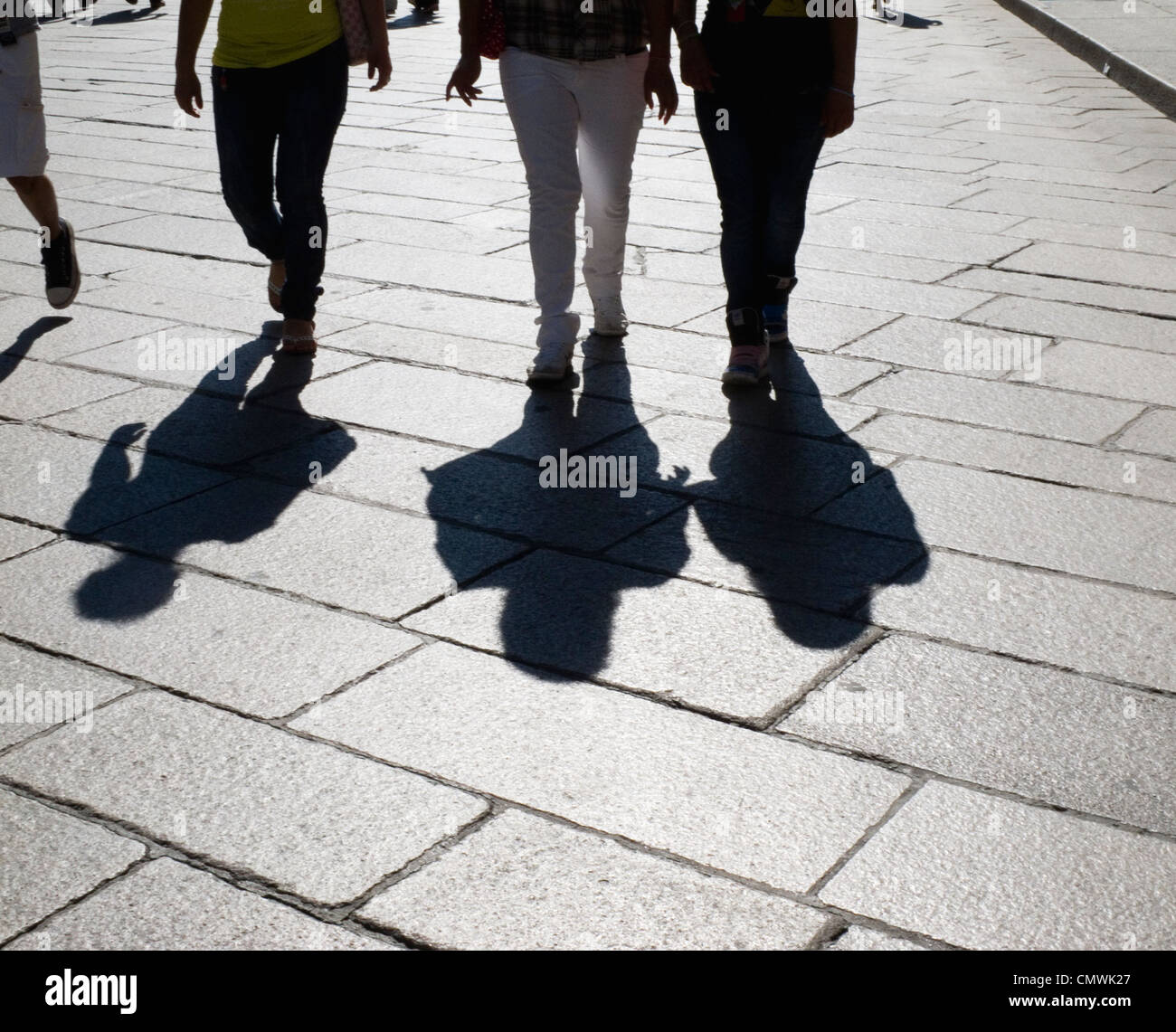 Silhouette of people walking along a pavement Stock Photo - Alamy