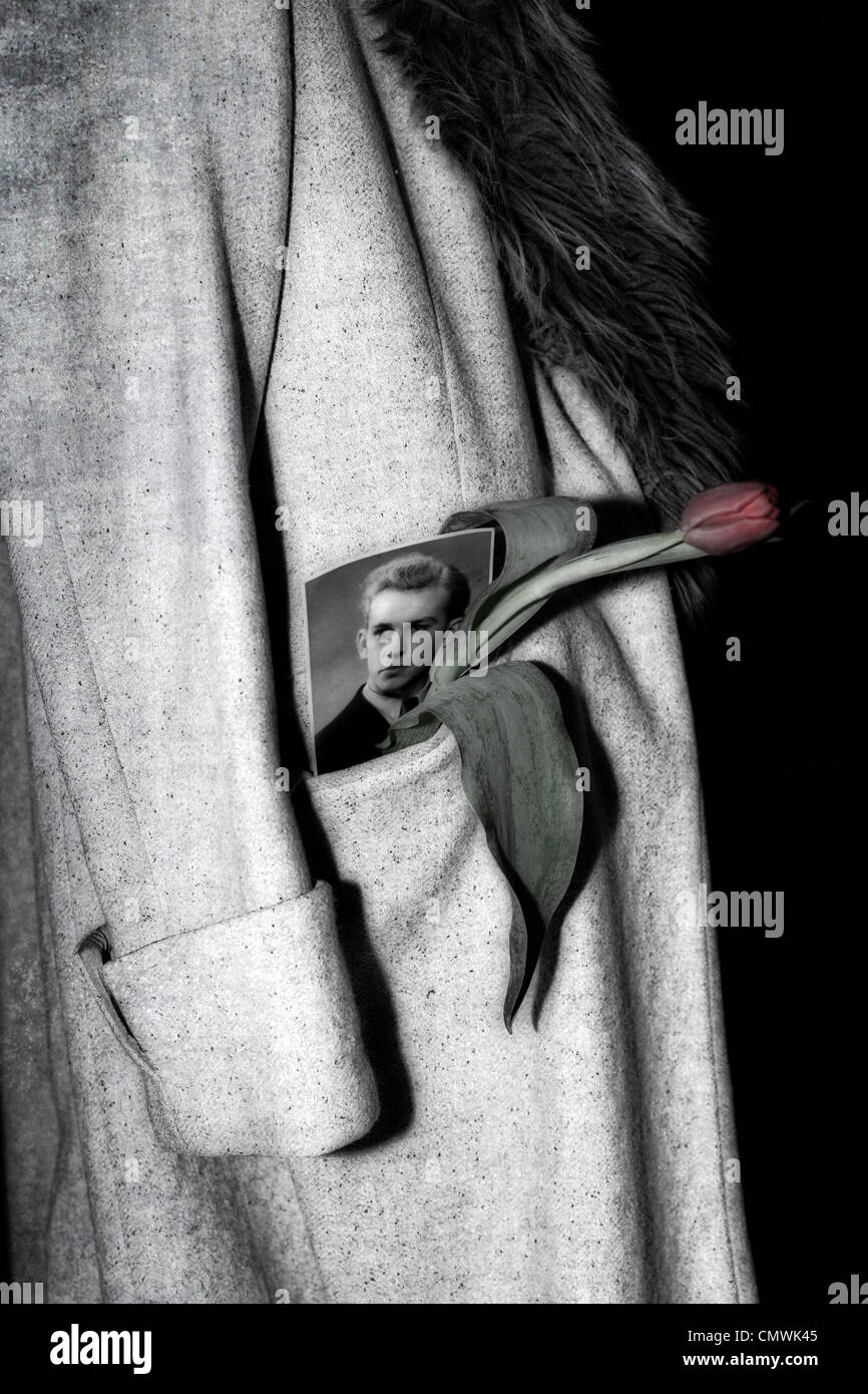 a coat with fur collar hanging over a chair, in the pocket a picture of a man and a tulip Stock Photo