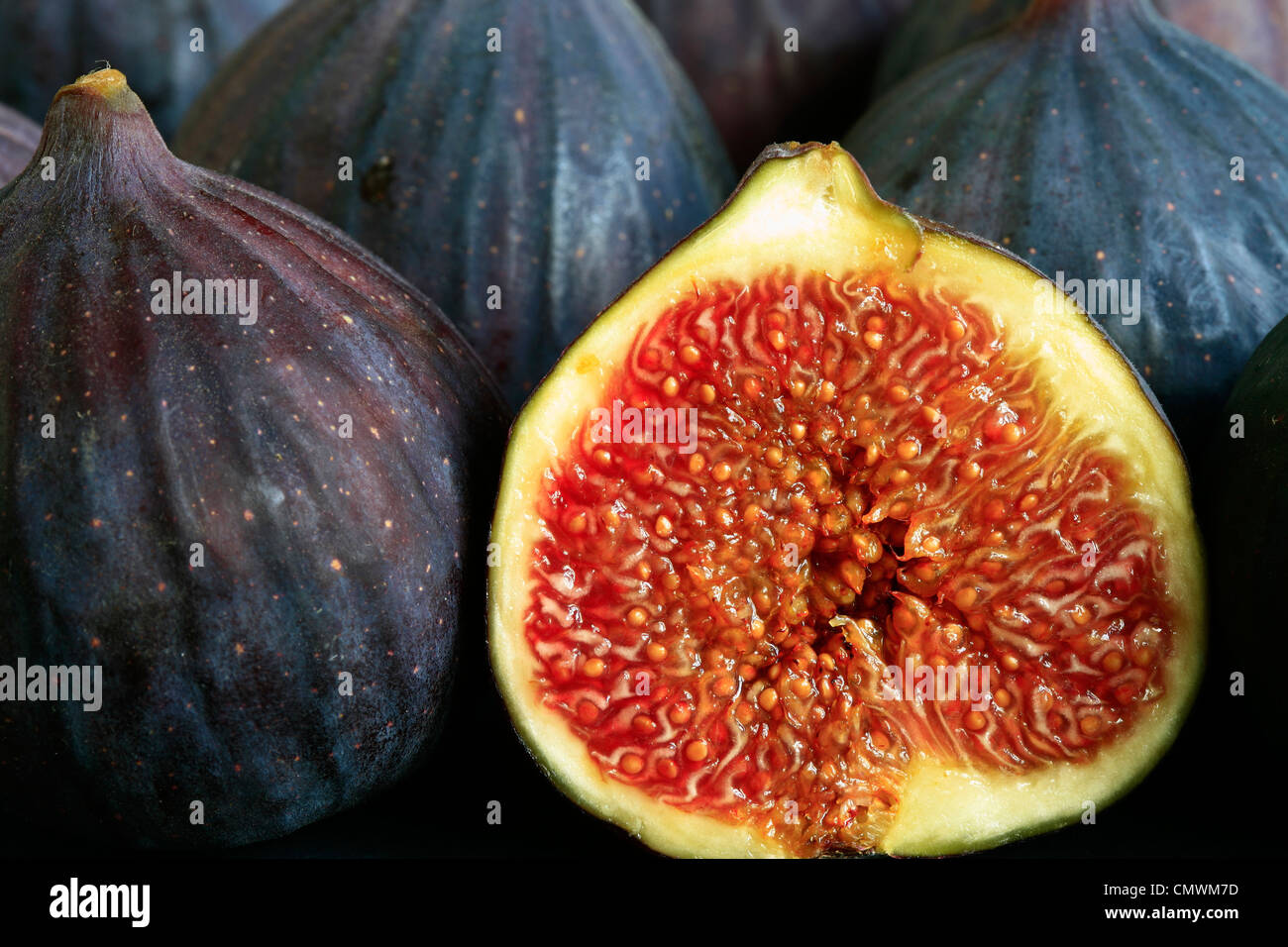 A close up of ripe figs with one cut in half showing the flesh Stock