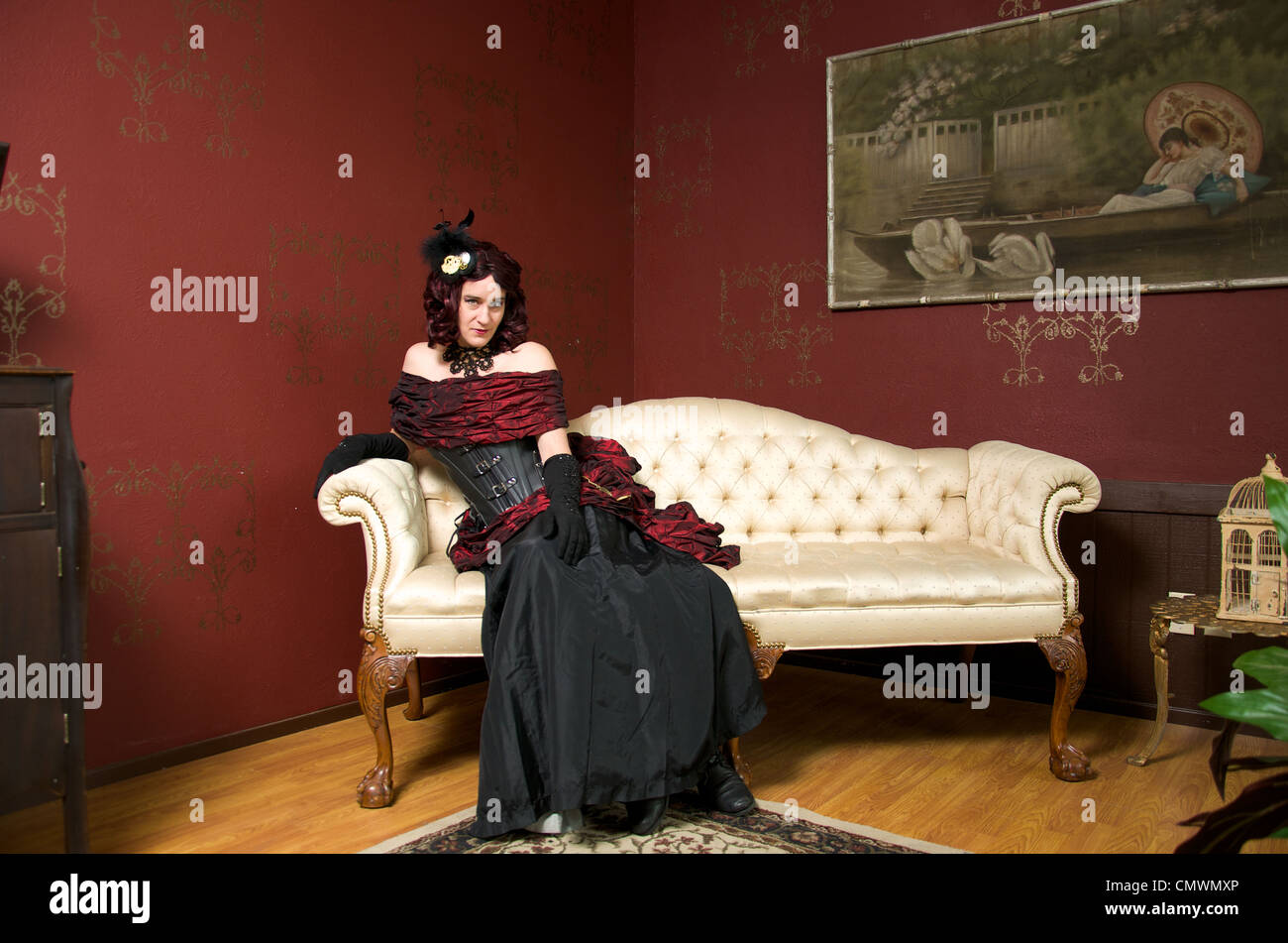 A Lady Dressed In Victorian Steampunk Outfit On White Couch