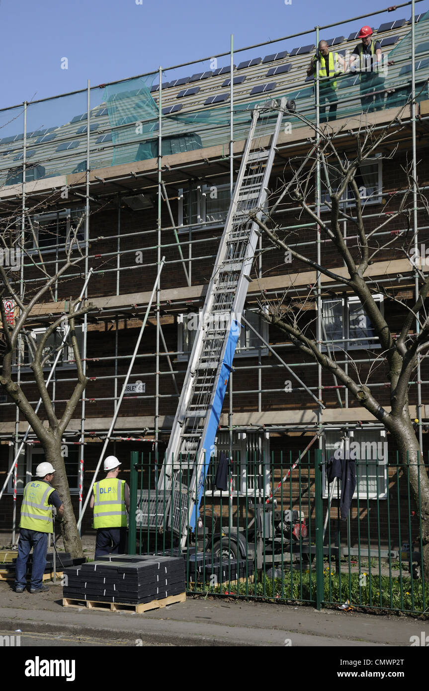 Workmen putting new roof tiles on block of houses waiting for new load