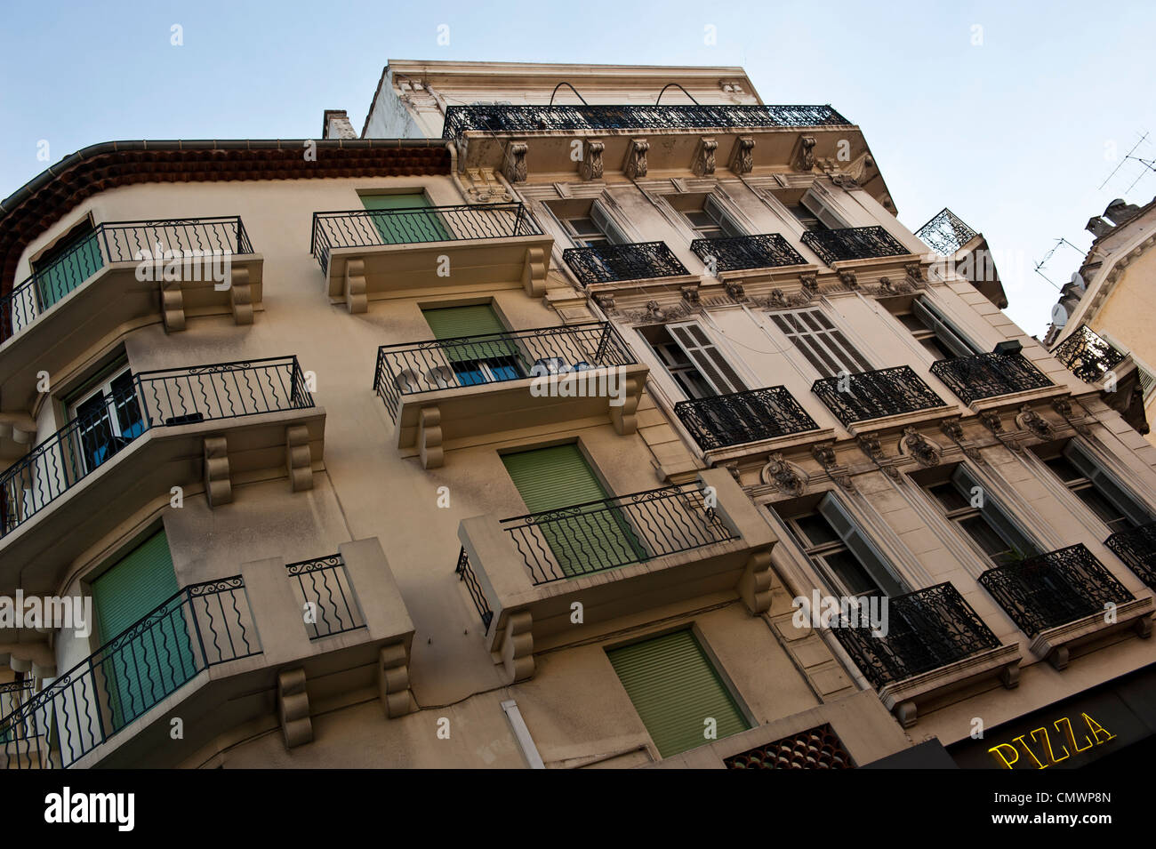 A photo of black balconies outside of beige buildings, taken at a cant angle during sunset. Stock Photo