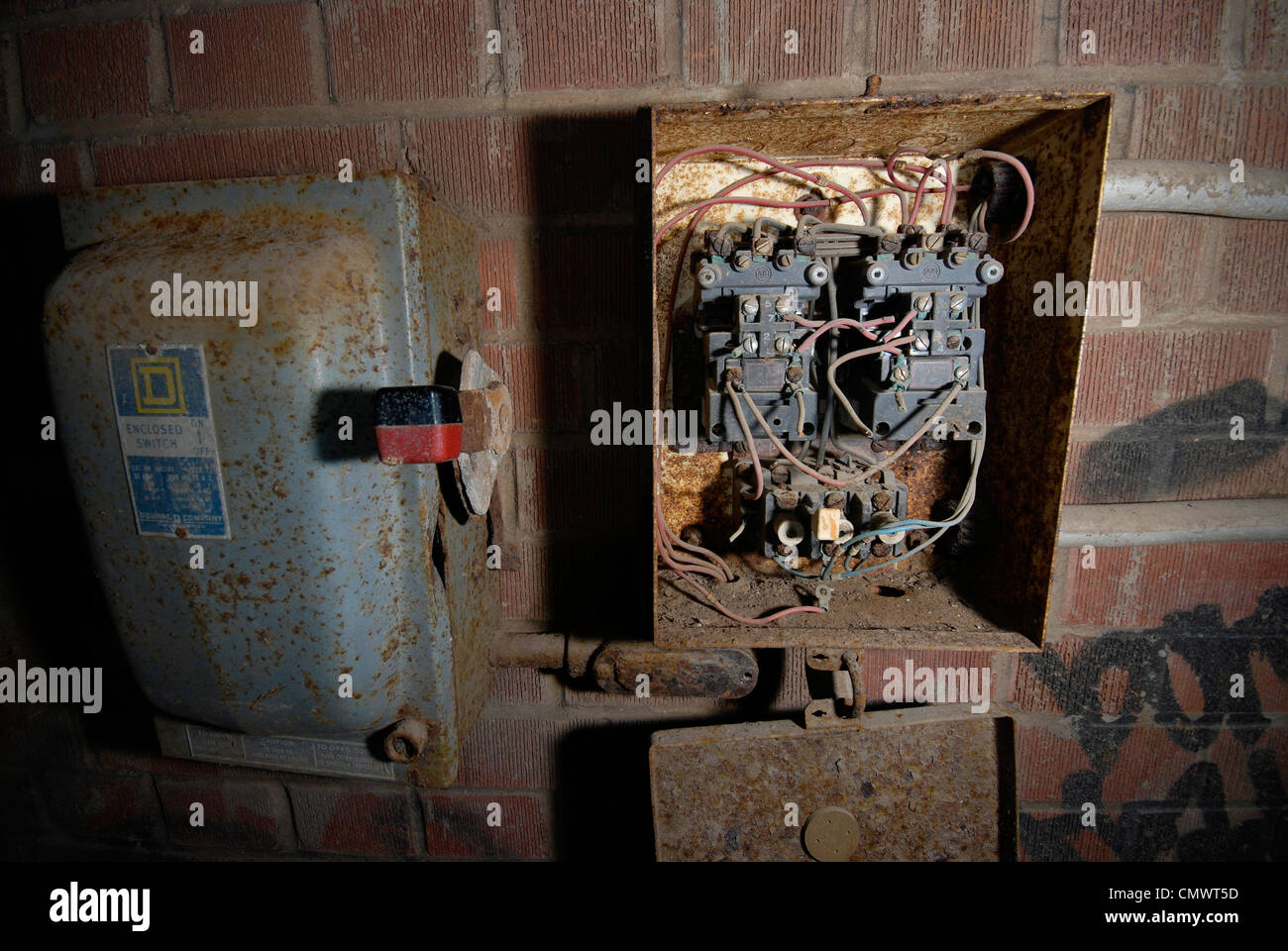 A broken down and decrepit old electrical panel box on the wall of an abandoned industrial factory. Stock Photo
