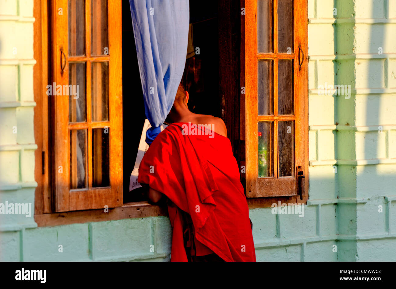 Young monk looking in window, Nyaungshwe, Inle Lake, Myanmar Stock Photo