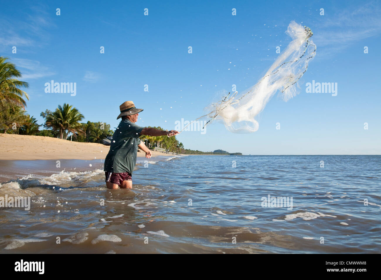 Man throwing cast net into sea.  Machans Beach, Cairns, Queensland, Australia Stock Photo