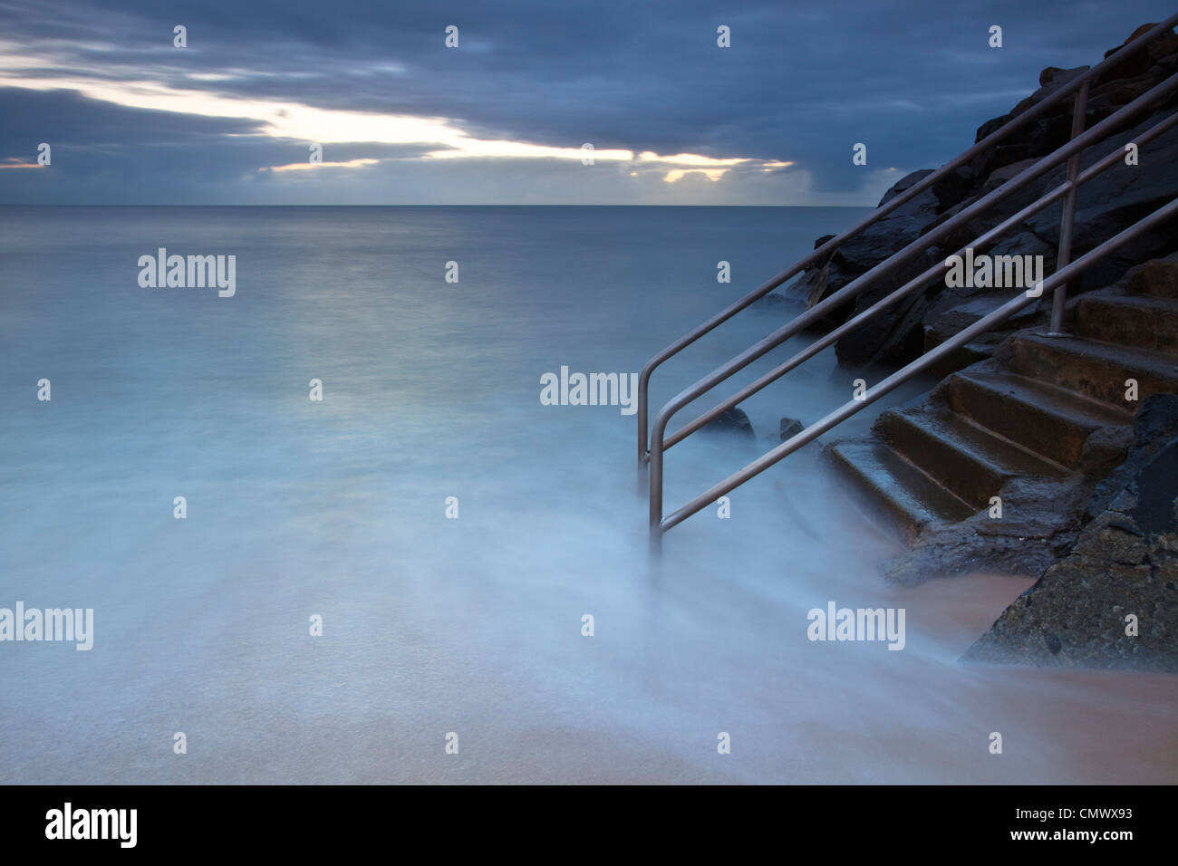 Waves washing over steps leading into sea.   Machans Beach, Cairns, Queensland, Australia Stock Photo
