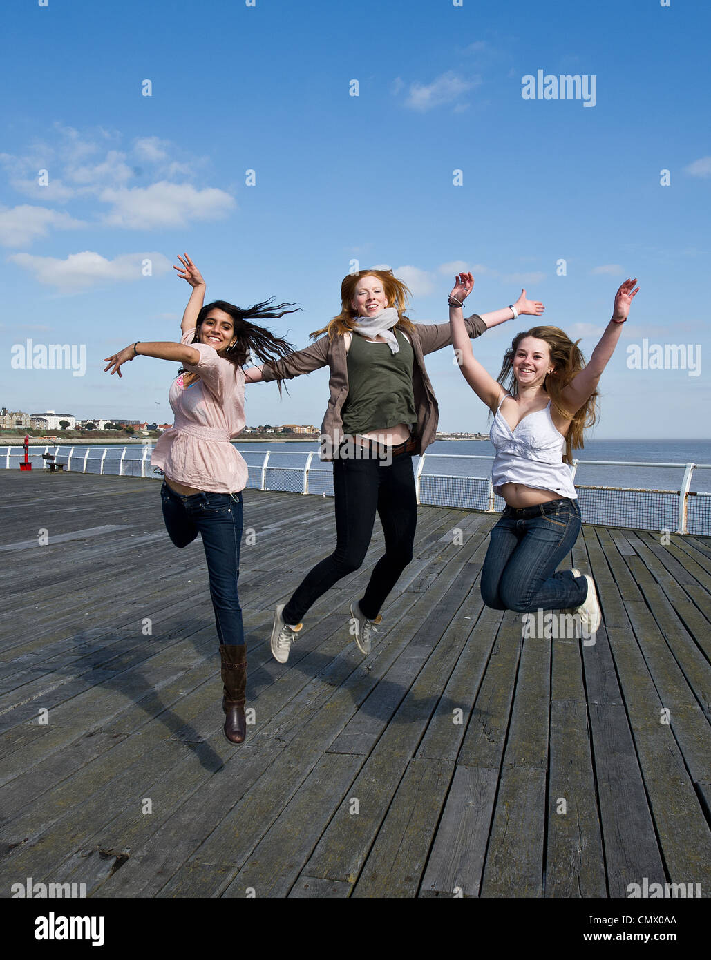 Three young girls jumping into the air Stock Photo