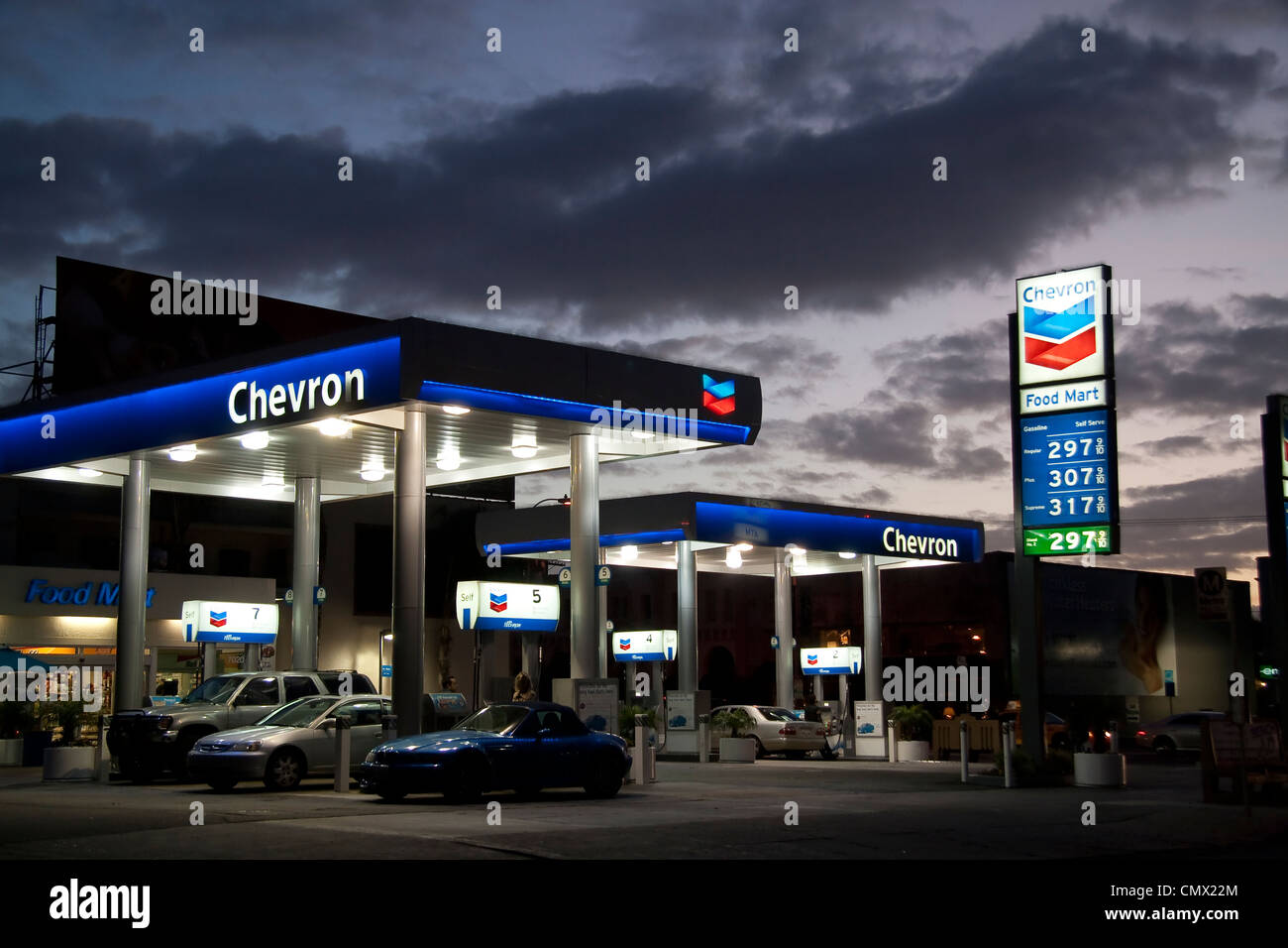 Chevron USA Gas Station under moody twilight sky showing silhouette of cars at gas pumps Stock Photo
