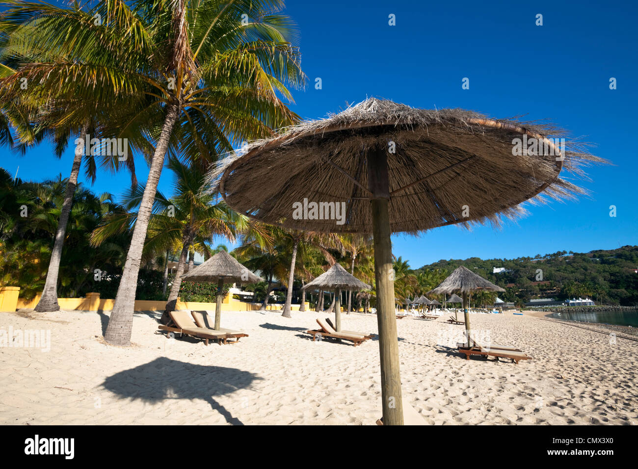Sun lounges and beach umbrellas on Catseye Beach. Hamilton Island, Whitsundays, Queensland, Australia Stock Photo