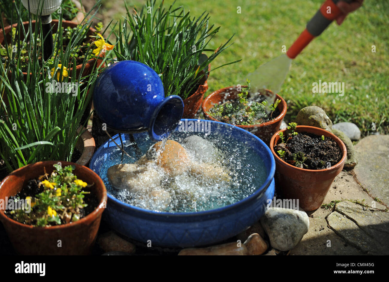 Using a garden hose to clean a solar powered water feature UK Stock Photo