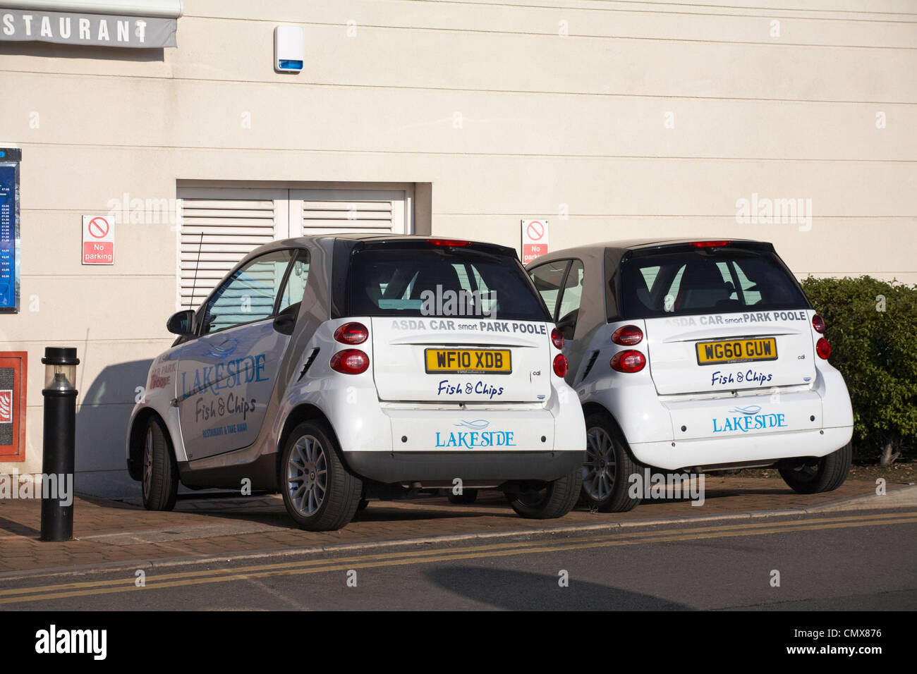 two personalised white Smart cars advertising Lakeside Fish & Chips parked outside restaurant in Asda car park Poole, Dorset UK in January Stock Photo