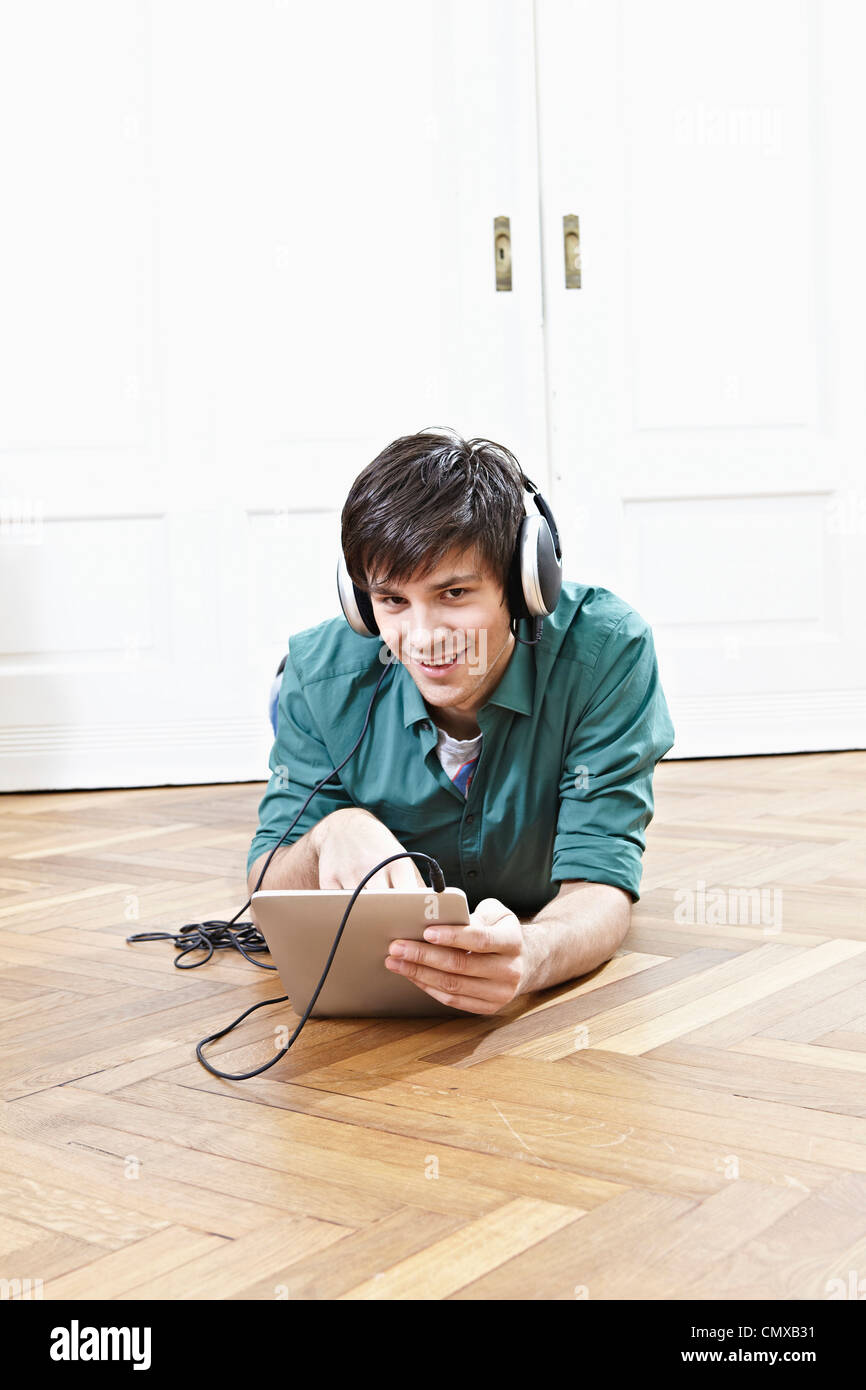Germany, Cologne, Young man with digital tablet and headphones, smiling, portrait Stock Photo