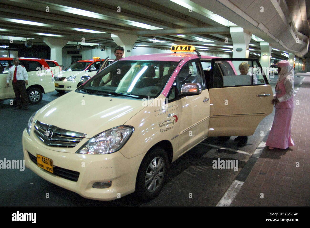 Airport pink ladies' taxi with driver  in traditional dress, Dubai, United Arab Emirates, UAE Stock Photo