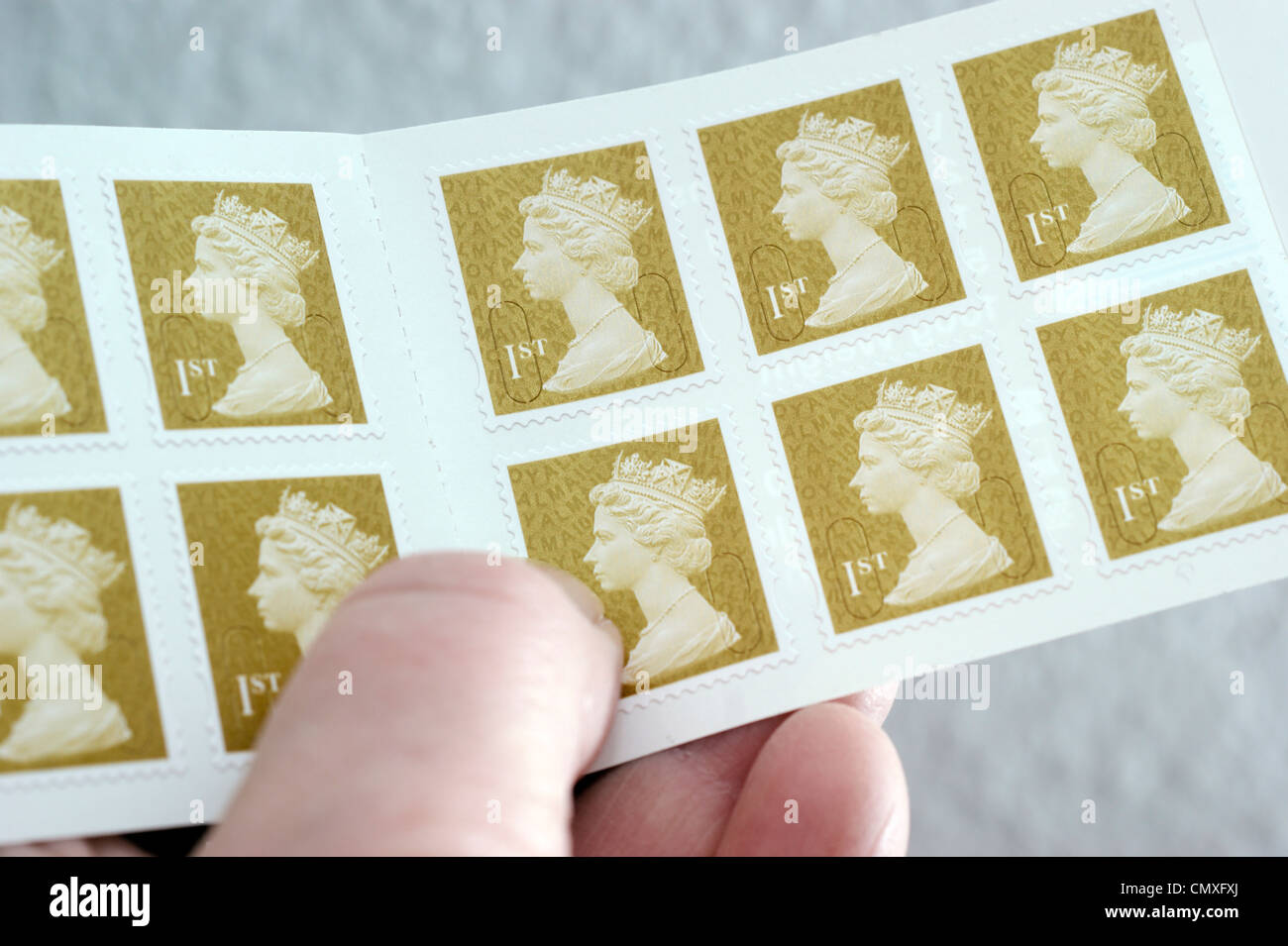Woman holding a book of 1st (first) class stamps Stock Photo