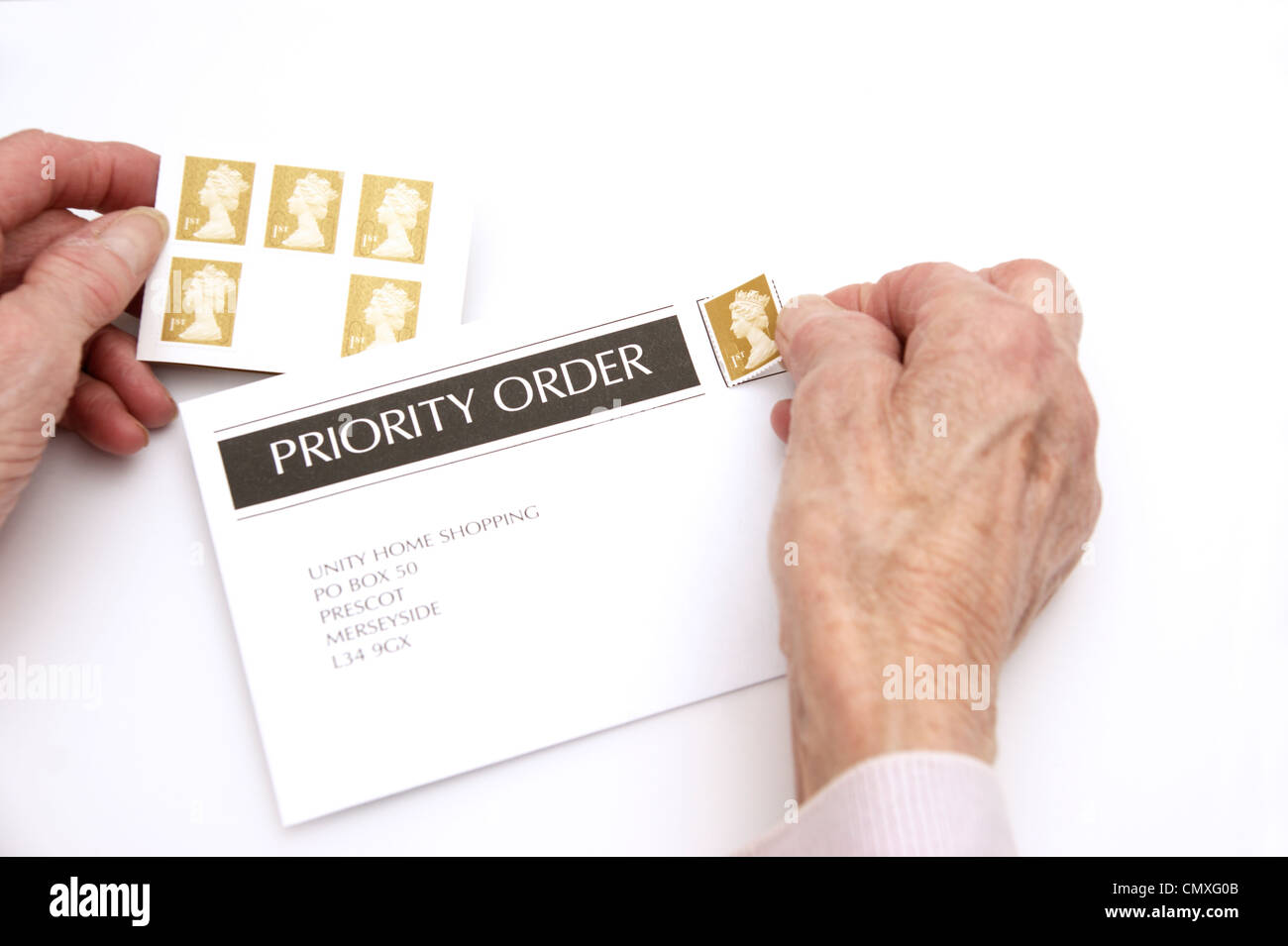 Elderly woman putting a 1st first class stamp on an envelope ready for posting (price increases 30th April 2012 Stock Photo