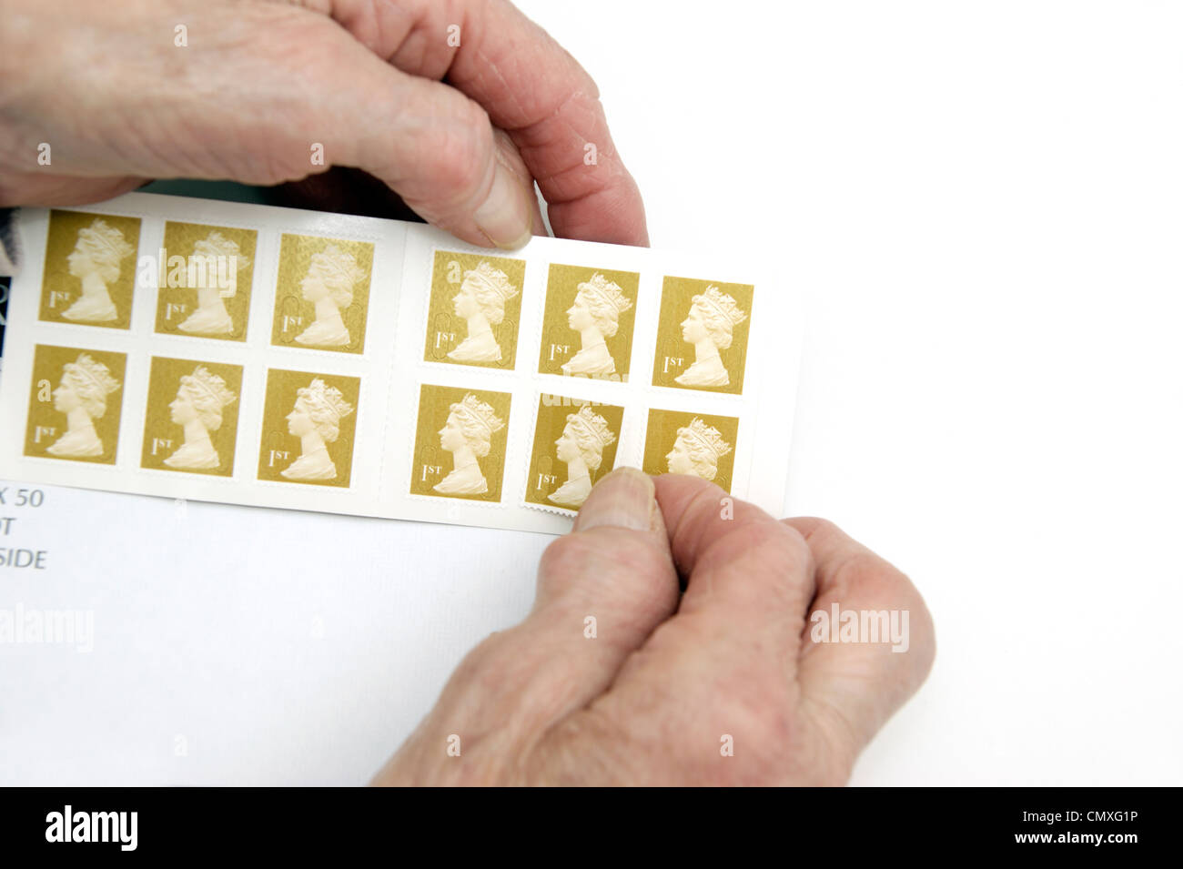 Elderly woman holding a book of 1st (first) class stamps Stock Photo