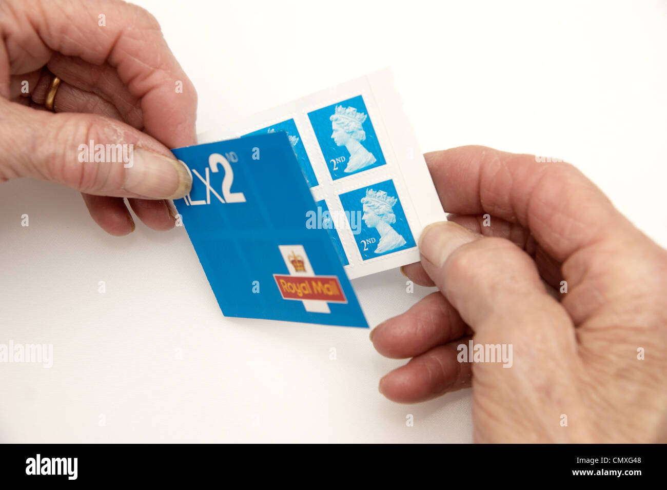 Elderly woman holding a book of 2nd second class stamps Stock Photo