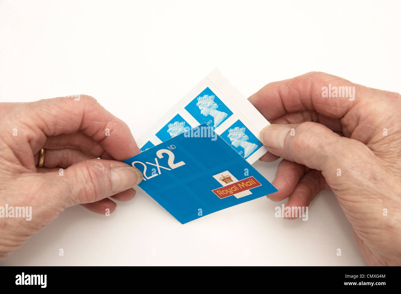 Elderly woman holding a book of 2nd second class stamps Stock Photo