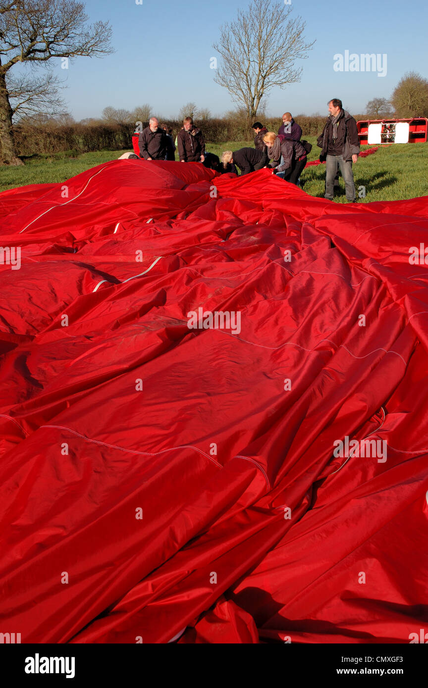 Passengers and crew help to pack up the Virgin balloon after a flight in South Norfolk, UK Stock Photo