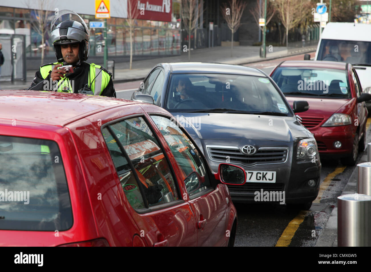 A traffic warden prepares to take a photo for evidence of a car that he has fined Stock Photo