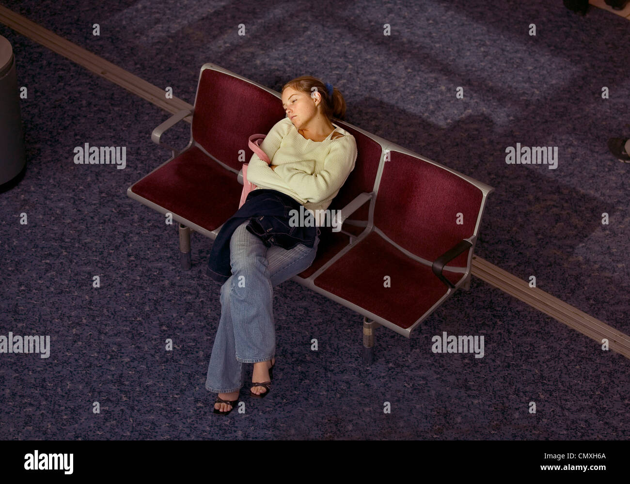 Woman passenger asleep in the seating area of departure lounge at Heathrow airport Stock Photo