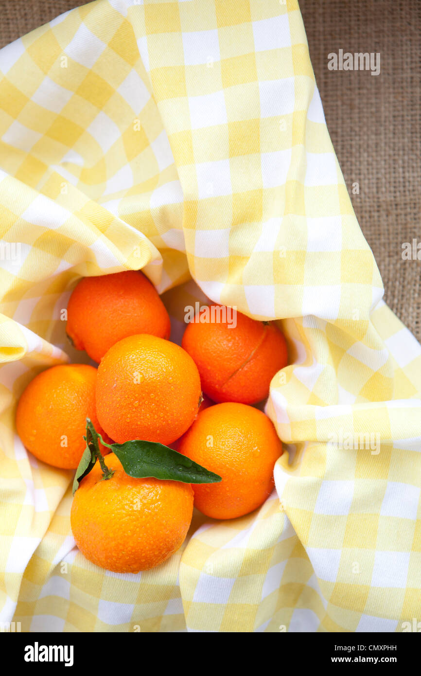 Satsumas photographed on yellow gingham and hessian. One satsuma has