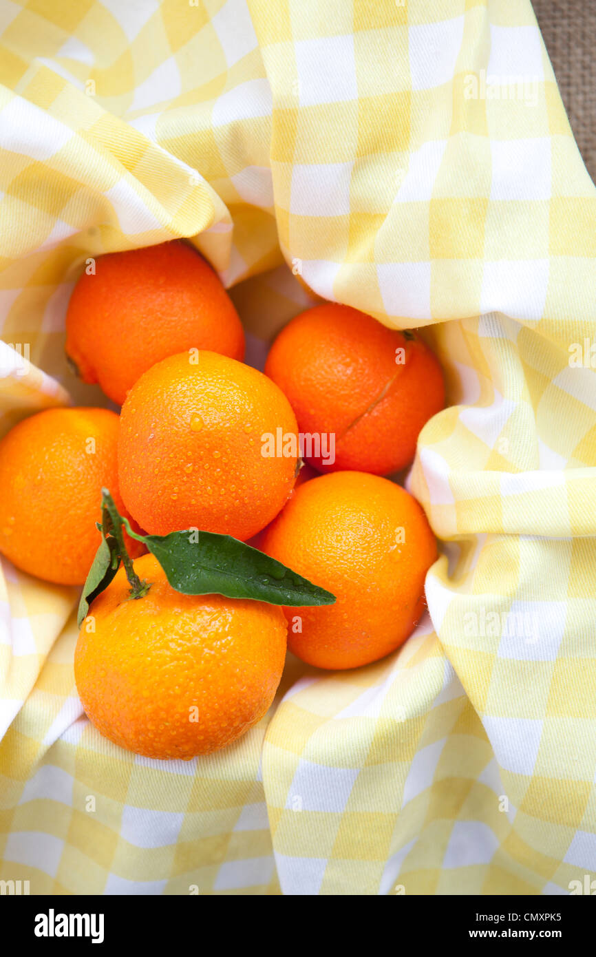 Satsumas photographed on yellow gingham and hessian. One satsuma has