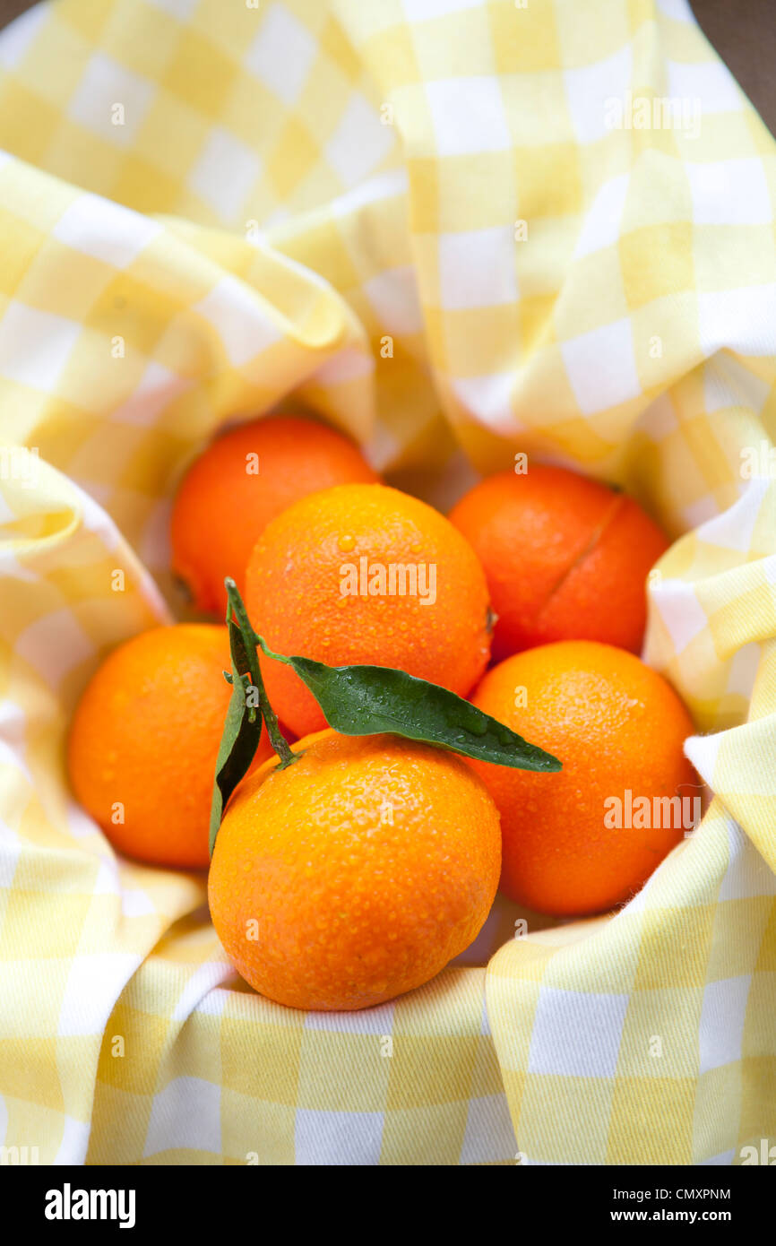 Satsumas photographed on yellow gingham and hessian. One satsuma has