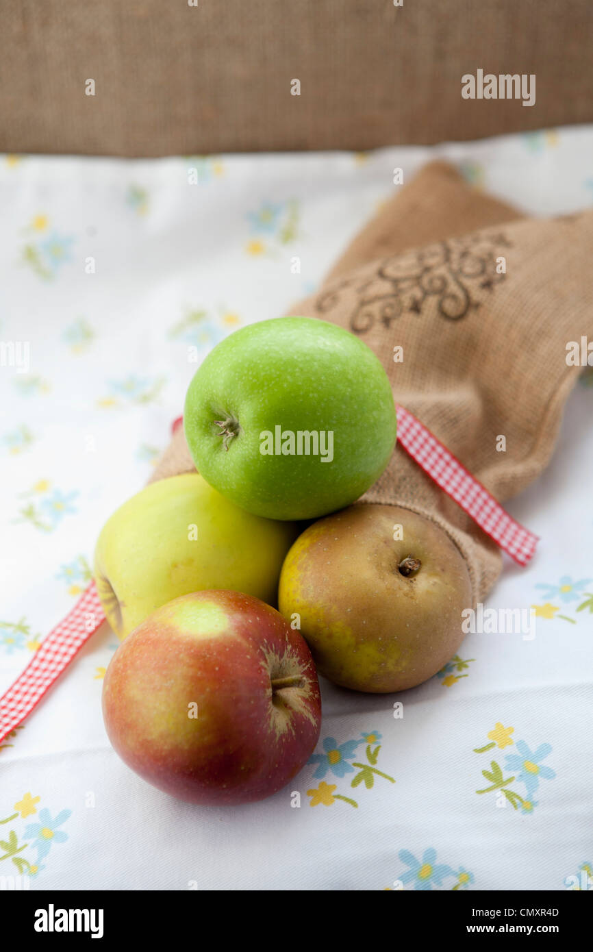 Apples with a hessian bag in natural light. Selection of fruit including Cox, Braeburn, Granny Smith, Golden Delicious, Jazz. Stock Photo