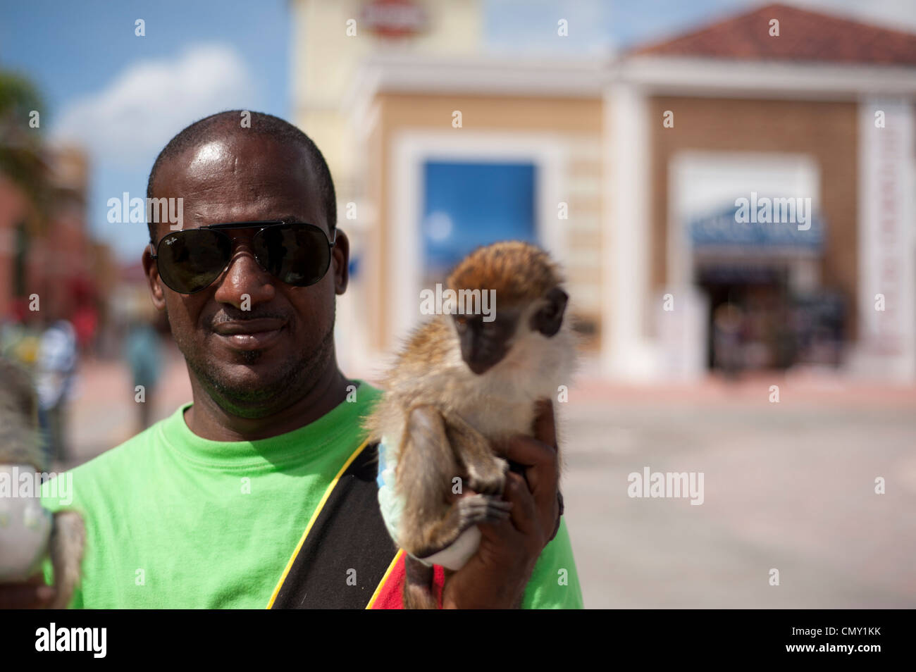 A local man wearing national colours holds his pet monkey, Basseterre