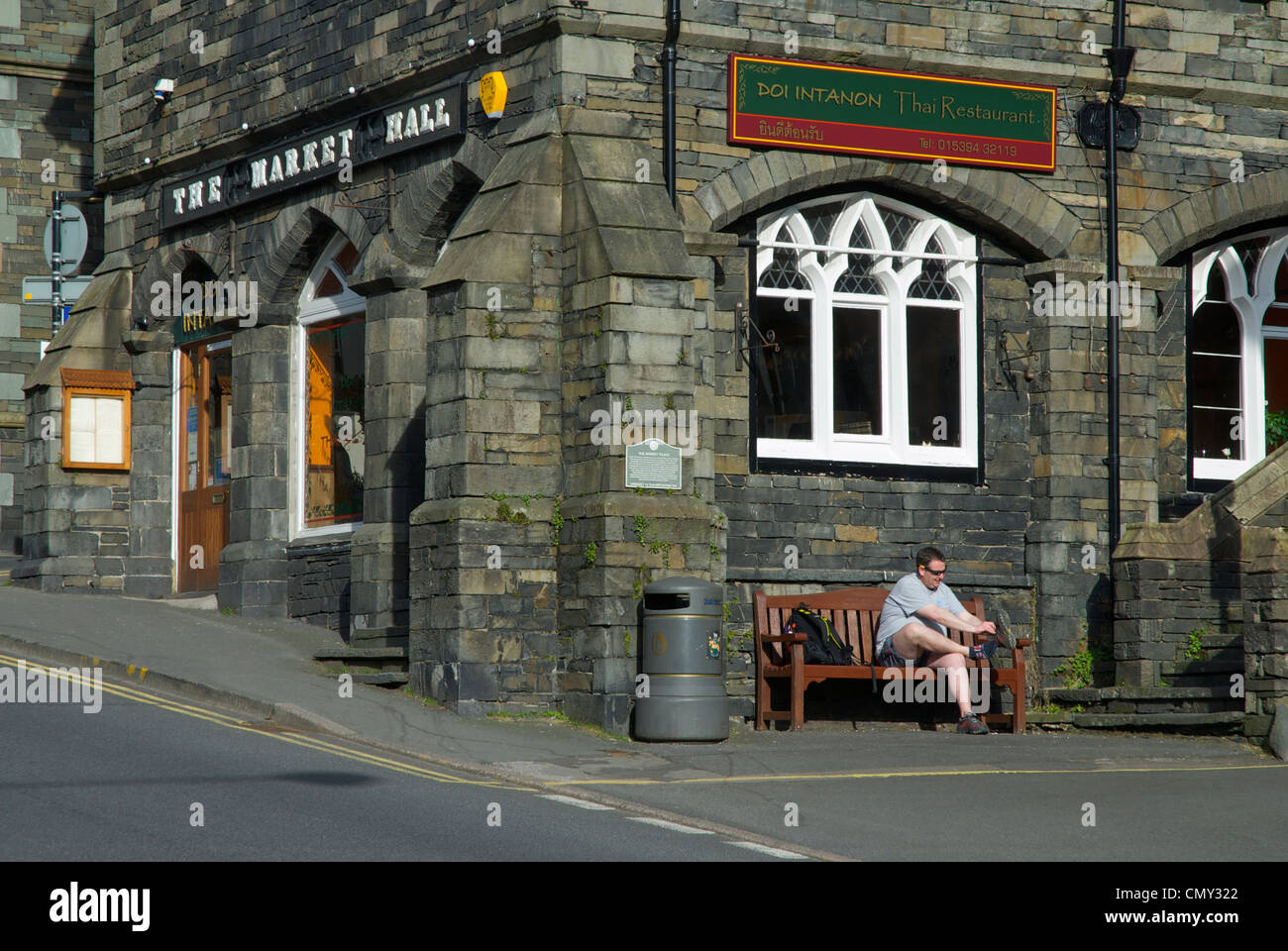 Man putting on his walking boot, sitting on a bench outside the Market