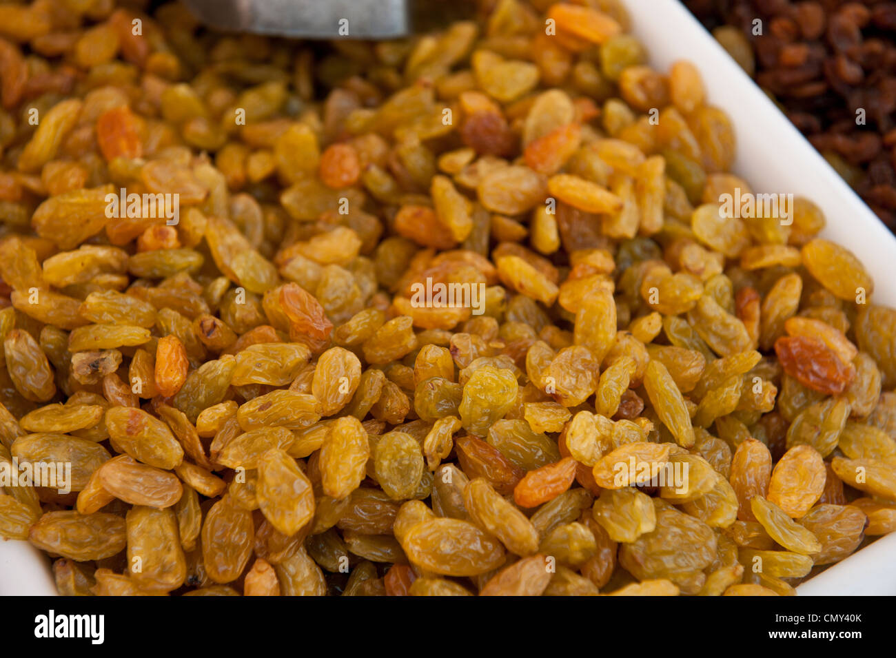 Macro image of yellow raisins in a white box next to brown raisins