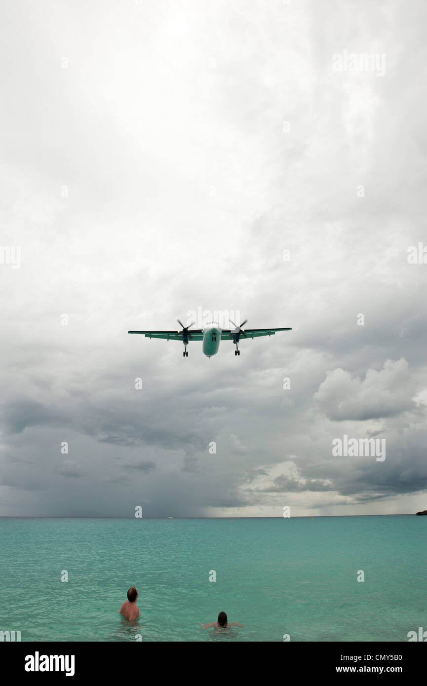 People looking onward as an airplane flies over the ocean. Stock Photo