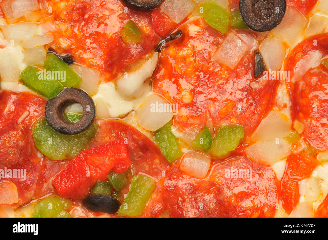 Macro close-up detail of pizza with cheese, pepperoni, red and green peppers, onions and black olives Stock Photo