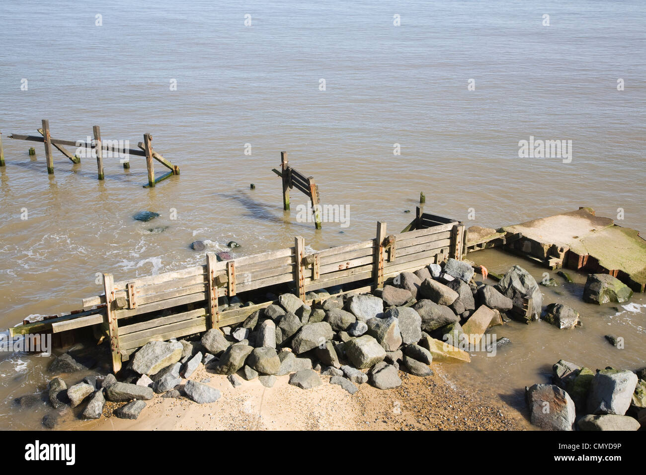 Rapid coastal erosion Happisburgh Norfolk England old wooden sea defences and more recent rock armour Stock Photo
