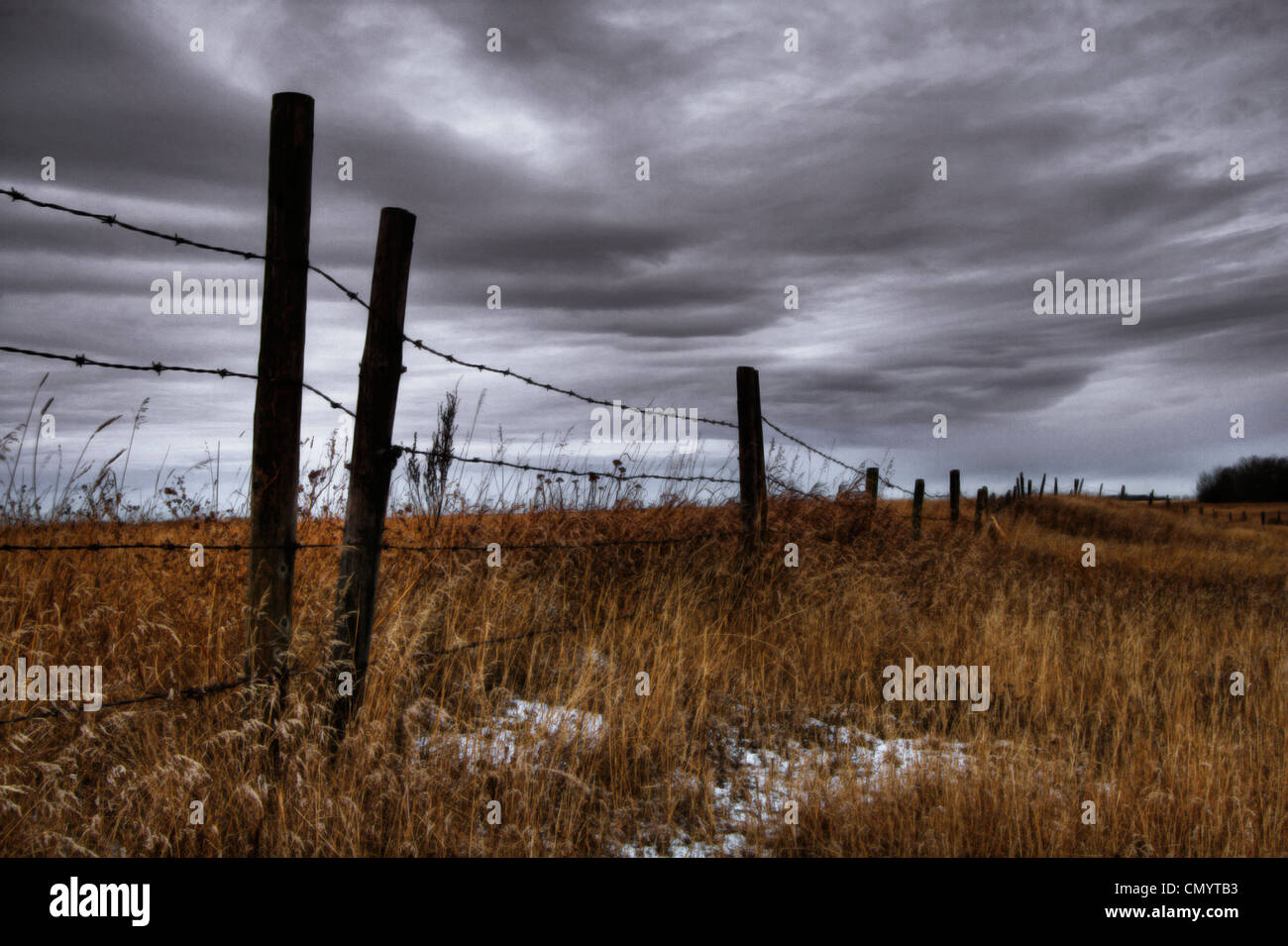 Barbed Wire Fence Posts with Dark Sky Behind, Alberta Stock Photo - Alamy