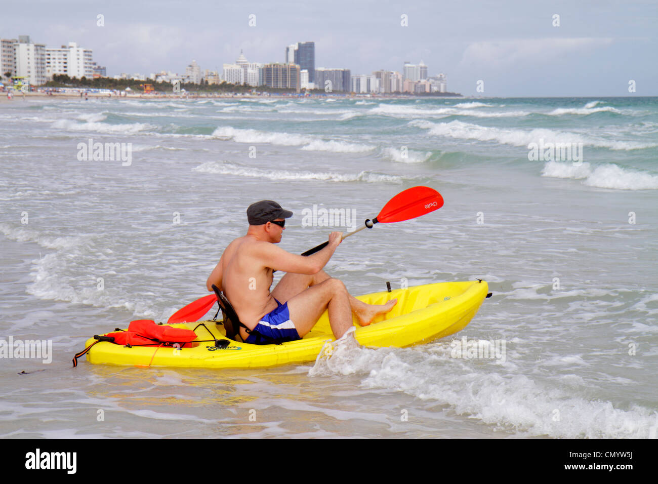 Miami Beach Florida,Atlantic Ocean,water,shore,surf,waves,water,man men male adult adults,bathing suit,yellow polyethylene plastic ocean kayak,draggin Stock Photo