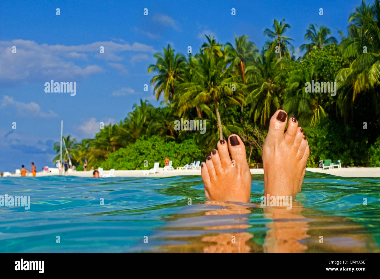 Womens feet, Palm trees at the beach of Biyadhoo Island, Indian Ocean, South Male Atoll, Maldives Stock Photo