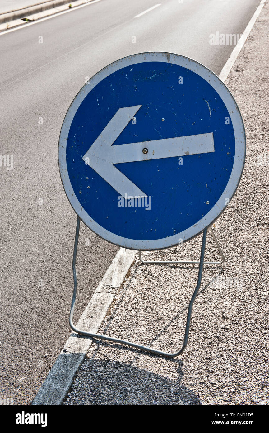 A macro shot of a blue, circular 'Left Turn' road sign in Villefranche-sur-Mer, France. Stock Photo