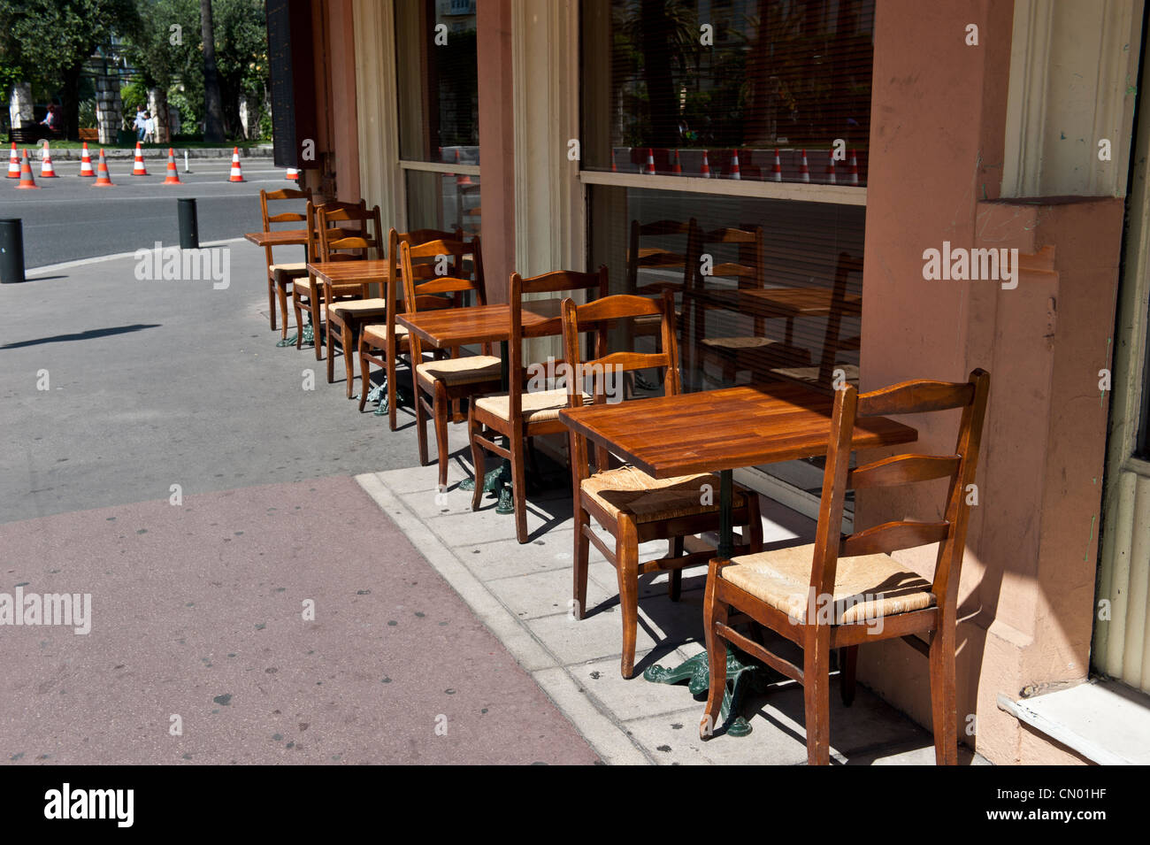 A column of wooden chair and table setups on a sidewalk. Stock Photo