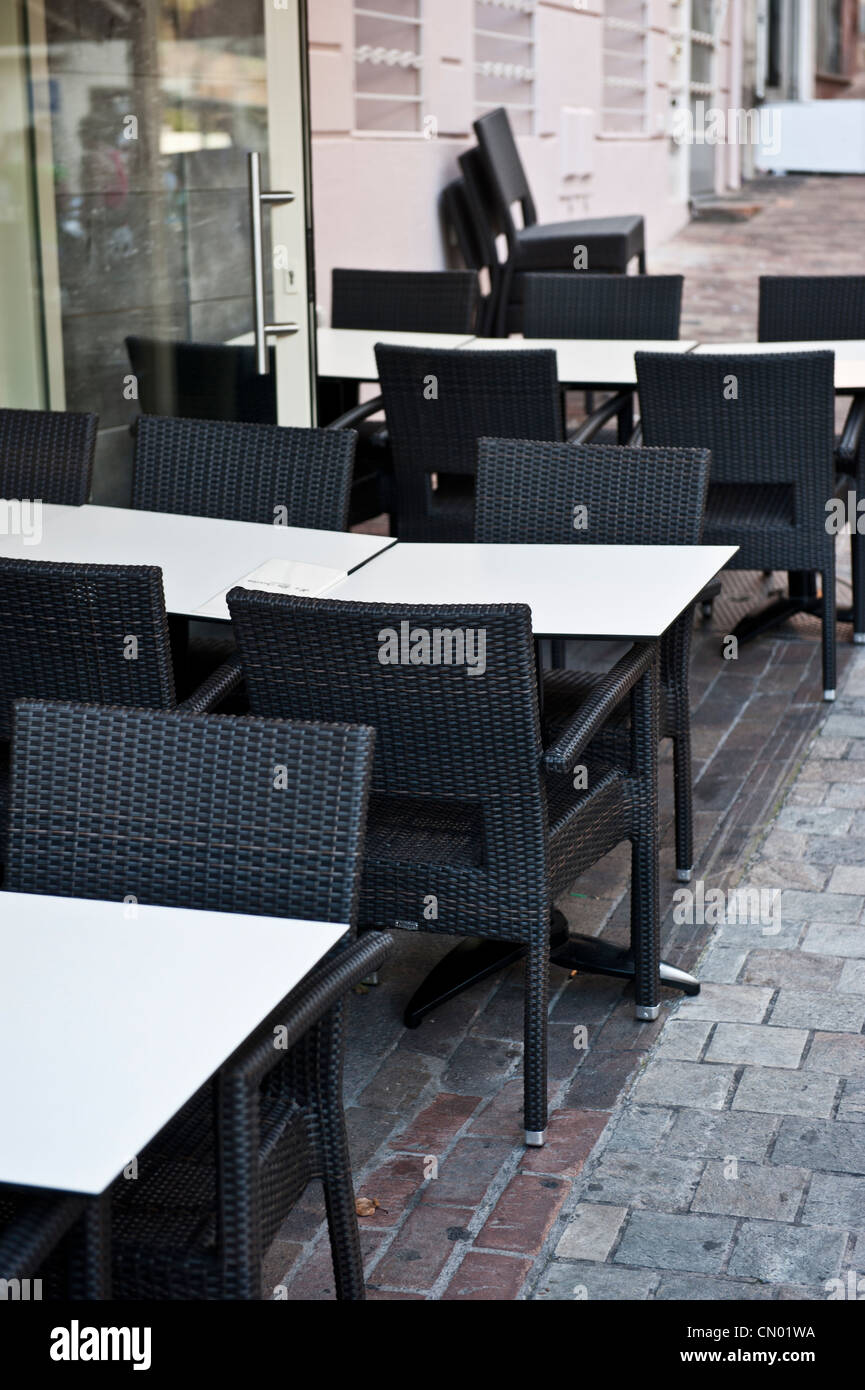 Empty white tables and black chairs outside of a restaurant cafe. Stock Photo