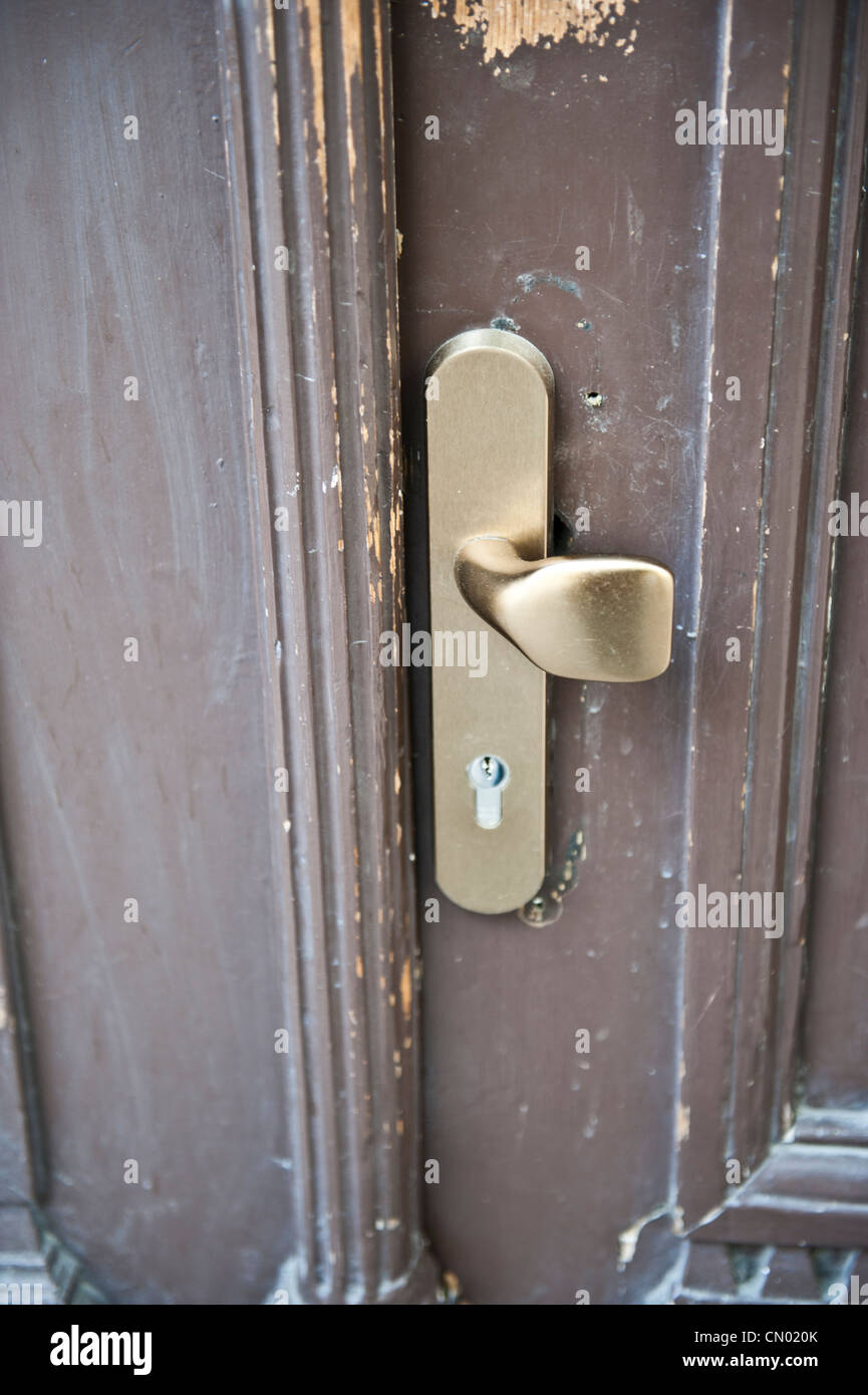 A gold lock on a chipped paint, rusted, brown door. Stock Photo