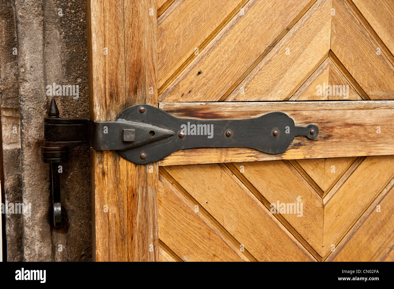 A bright color shot of a black latch on a light wooden door. Stock Photo