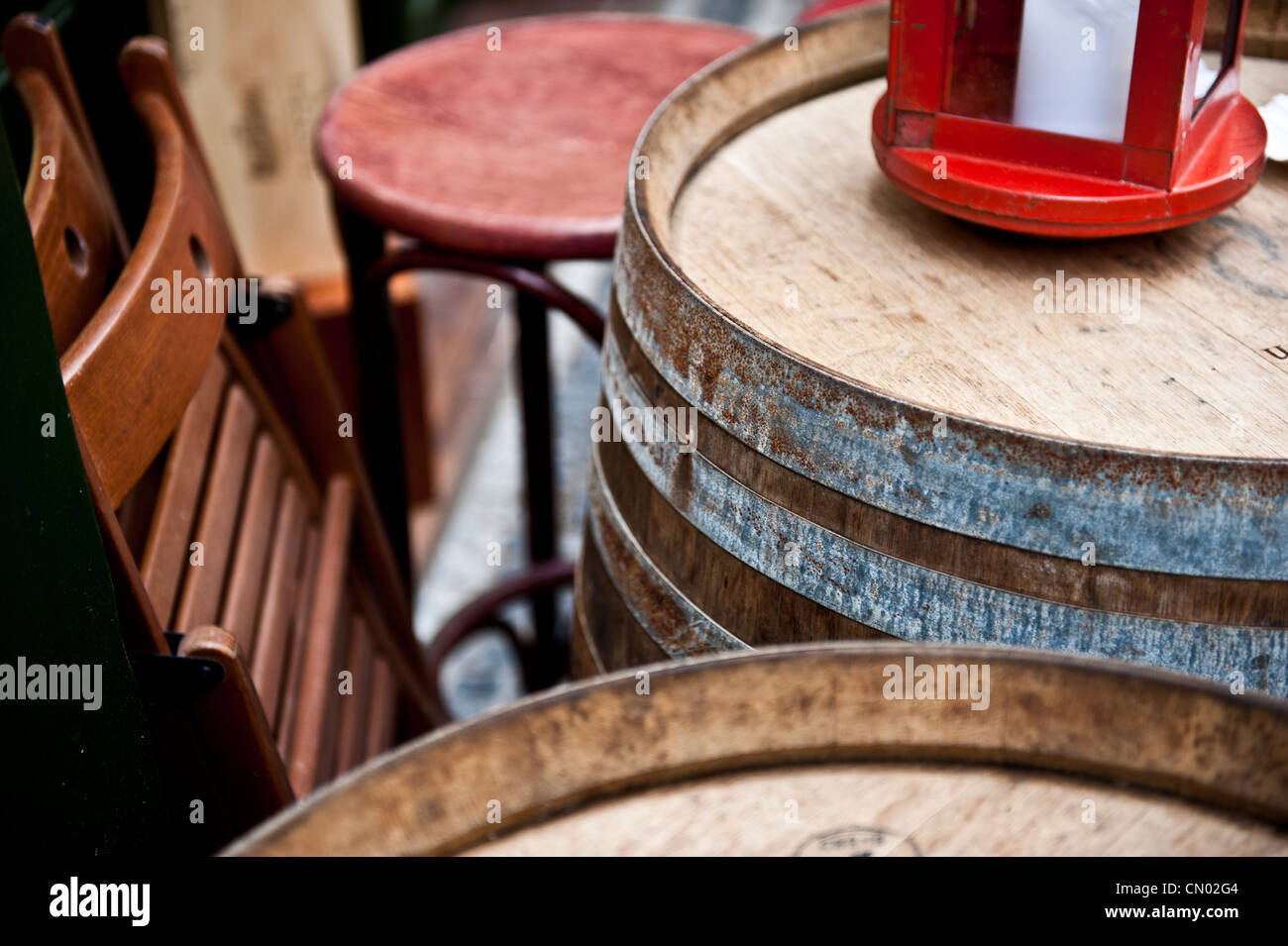 A red object on top of a wooden beer barrel outside of a restaurant. Stock Photo