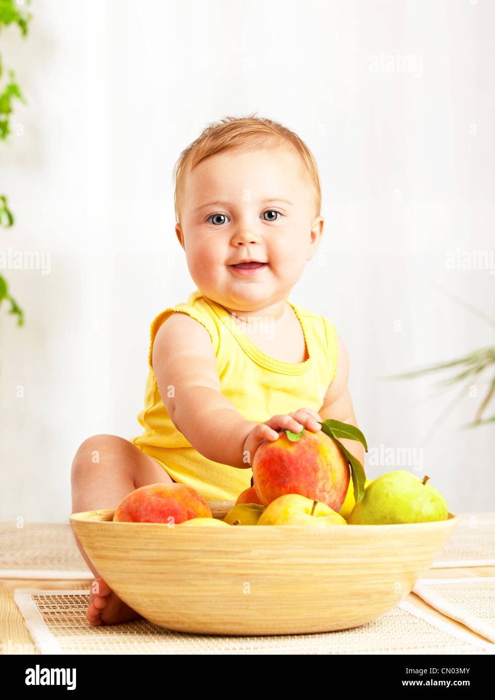Little baby holding fresh fruits, closeup portrait, concept of health