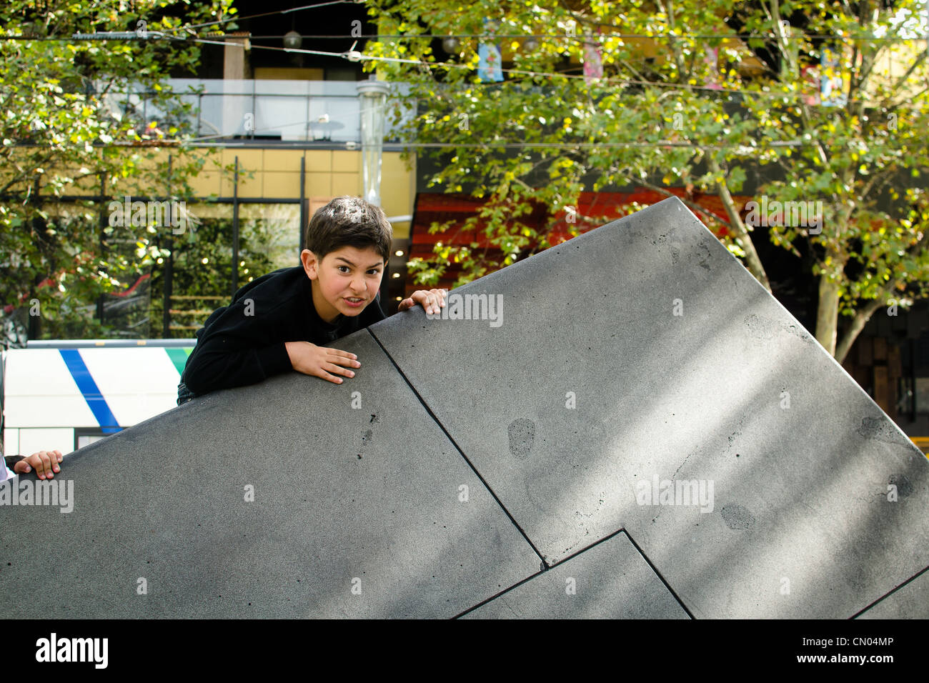 A boy climbing onto an art sculpture outside the Victorian State Library Melbourne Stock Photo