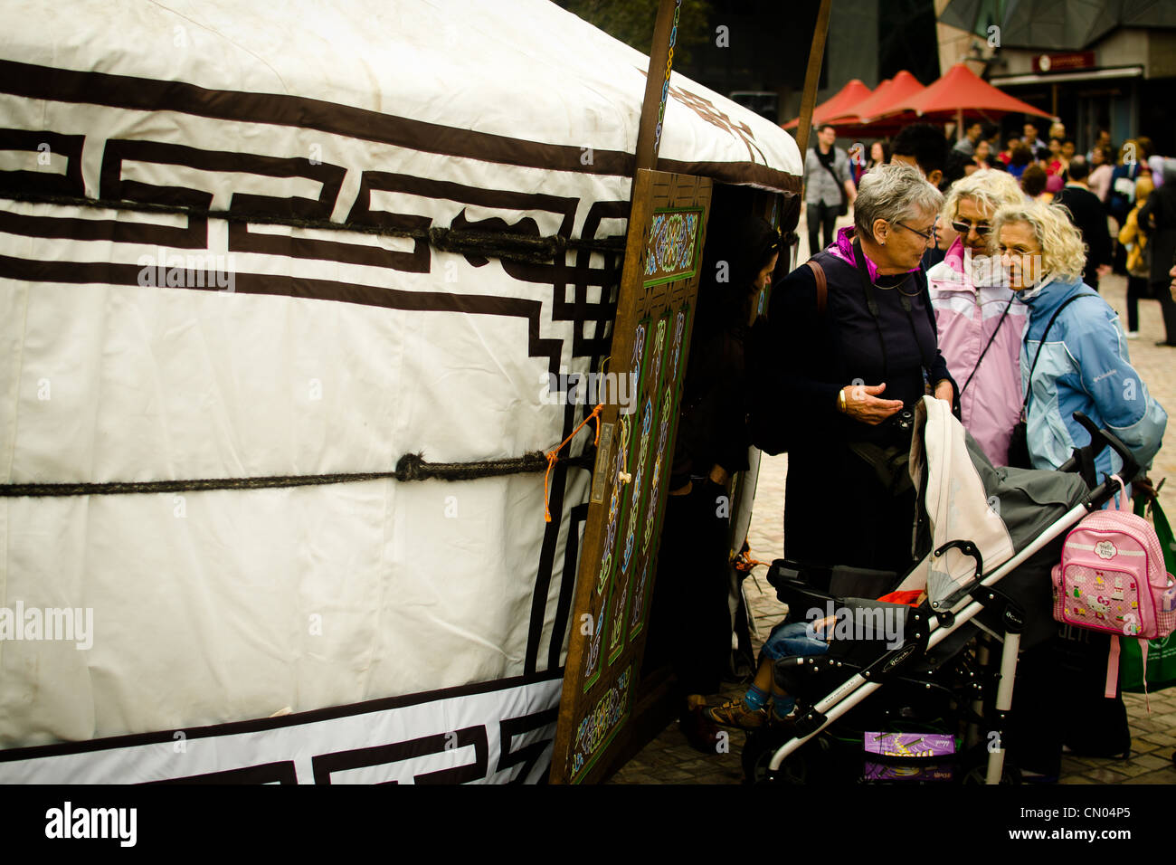 3 elderly women having discussion as they inspect a Mongolian hut in the multicultural festival Stock Photo