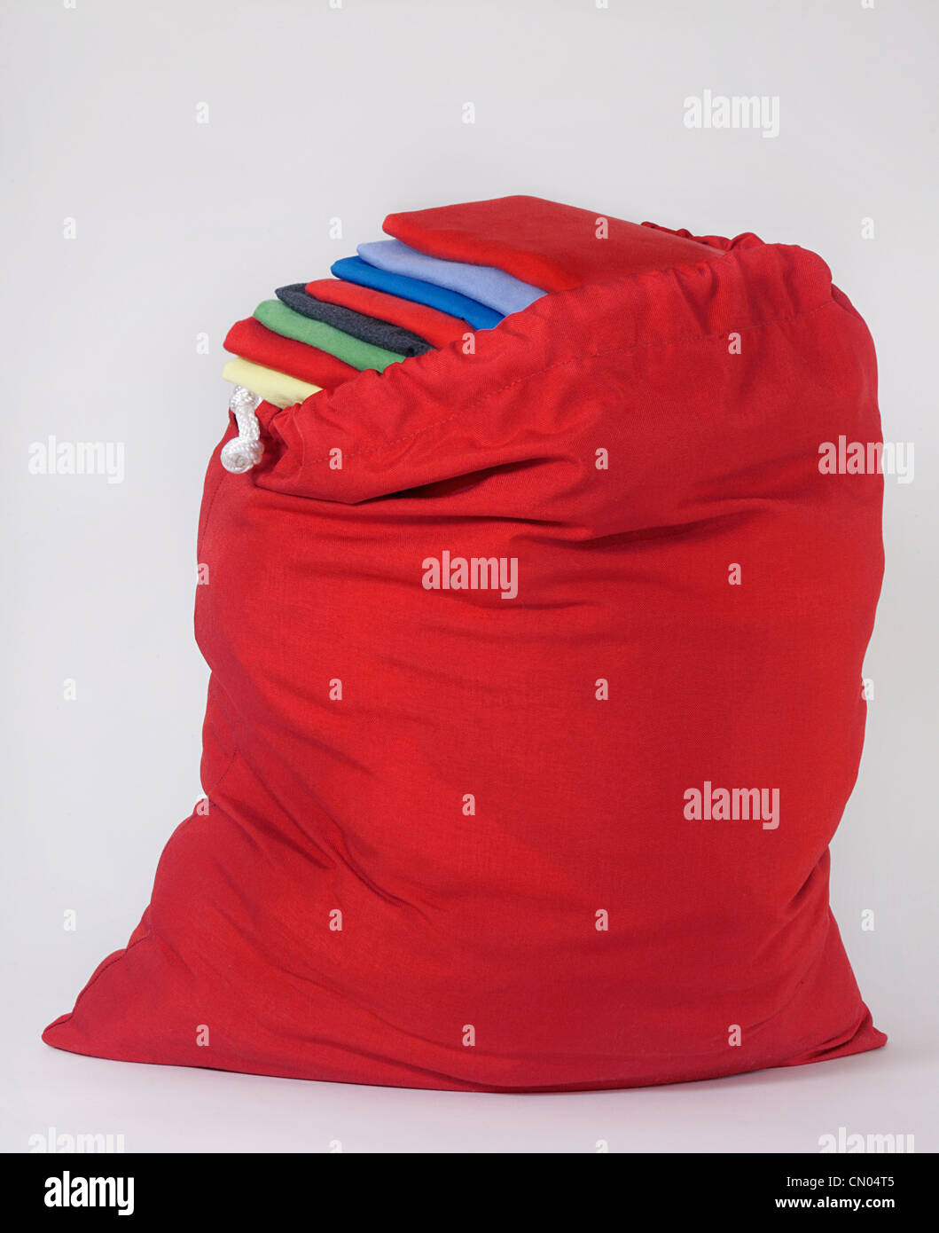 Bright red laundry bag with neatly folded laundry of various colors
